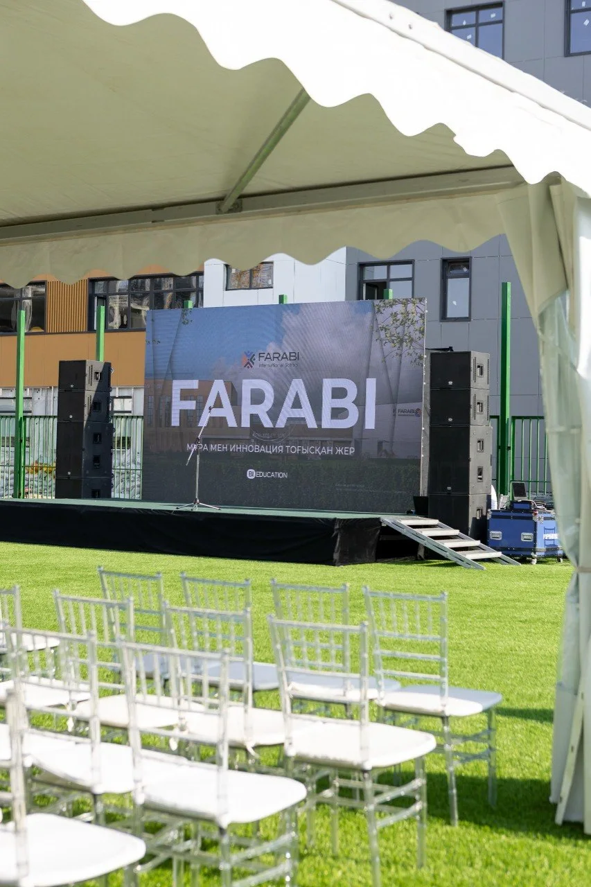 Сцена церемонии с брендированным задником FARABI и звуковыми линейными массивами, ряды стульев для гостей